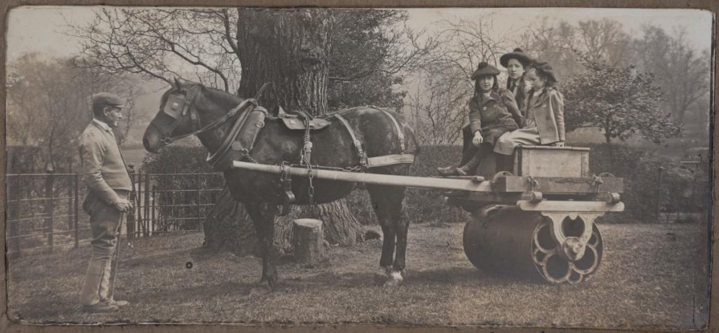 Black and white photograph of Bruce children having fun on the garden roller drawn by Spider and led by John Bird.