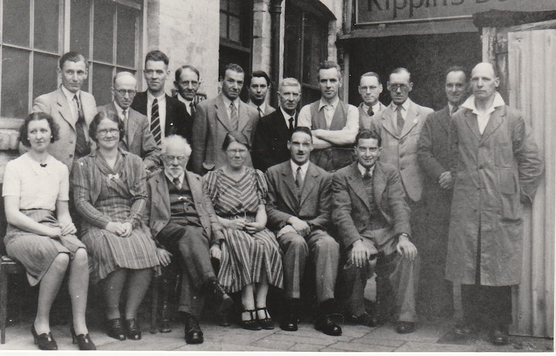 Black and white group photograph with Mollie Rippin, (front row, centre), outside Rippin's bookshop in Leicester. 